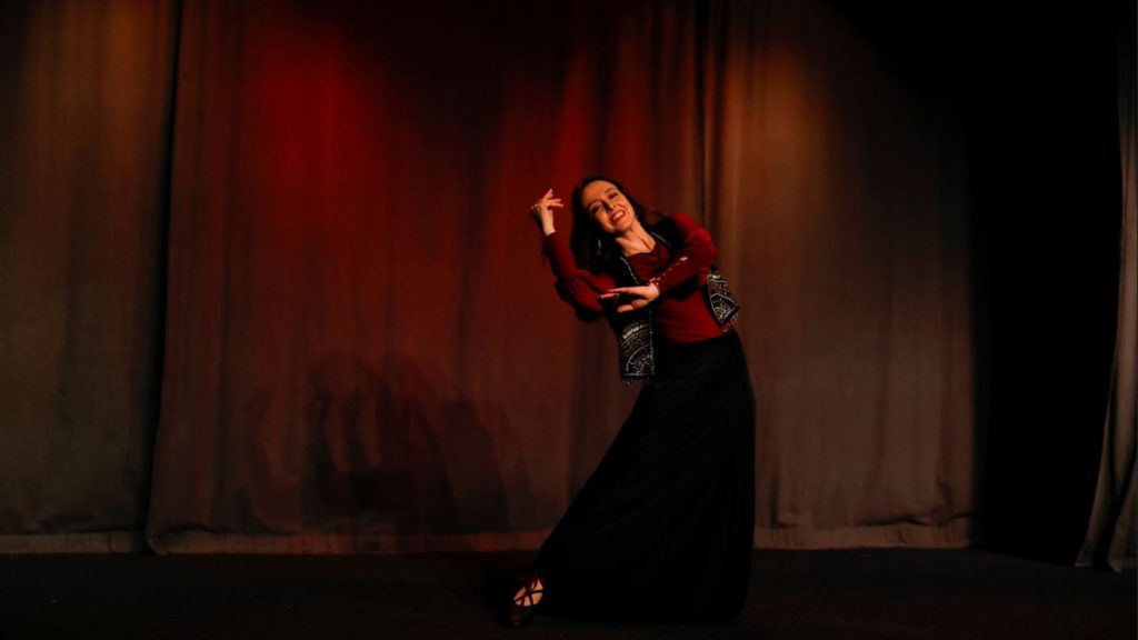 Eine Frau wiegt sich vor dunkelrotem Hintergrund zur Seite