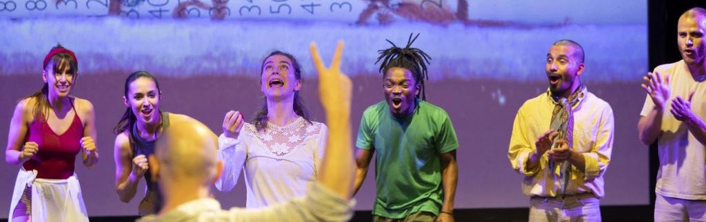 Menschen stehen auf Bühne und singen und klatschen